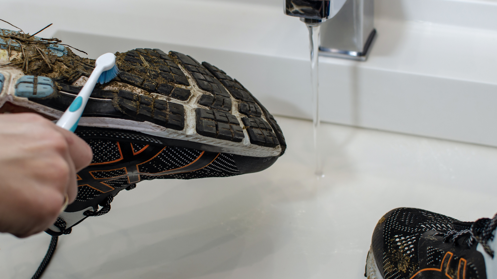 Person cleaning their running shoes that are covered in mud