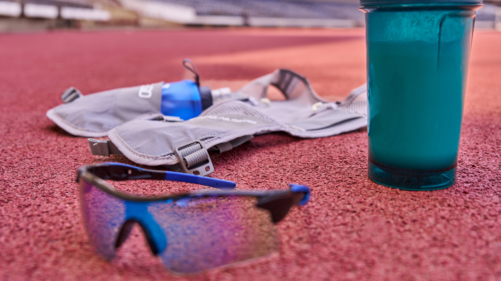 Running accessories on a running track. Including running vest, glasses and water bottle