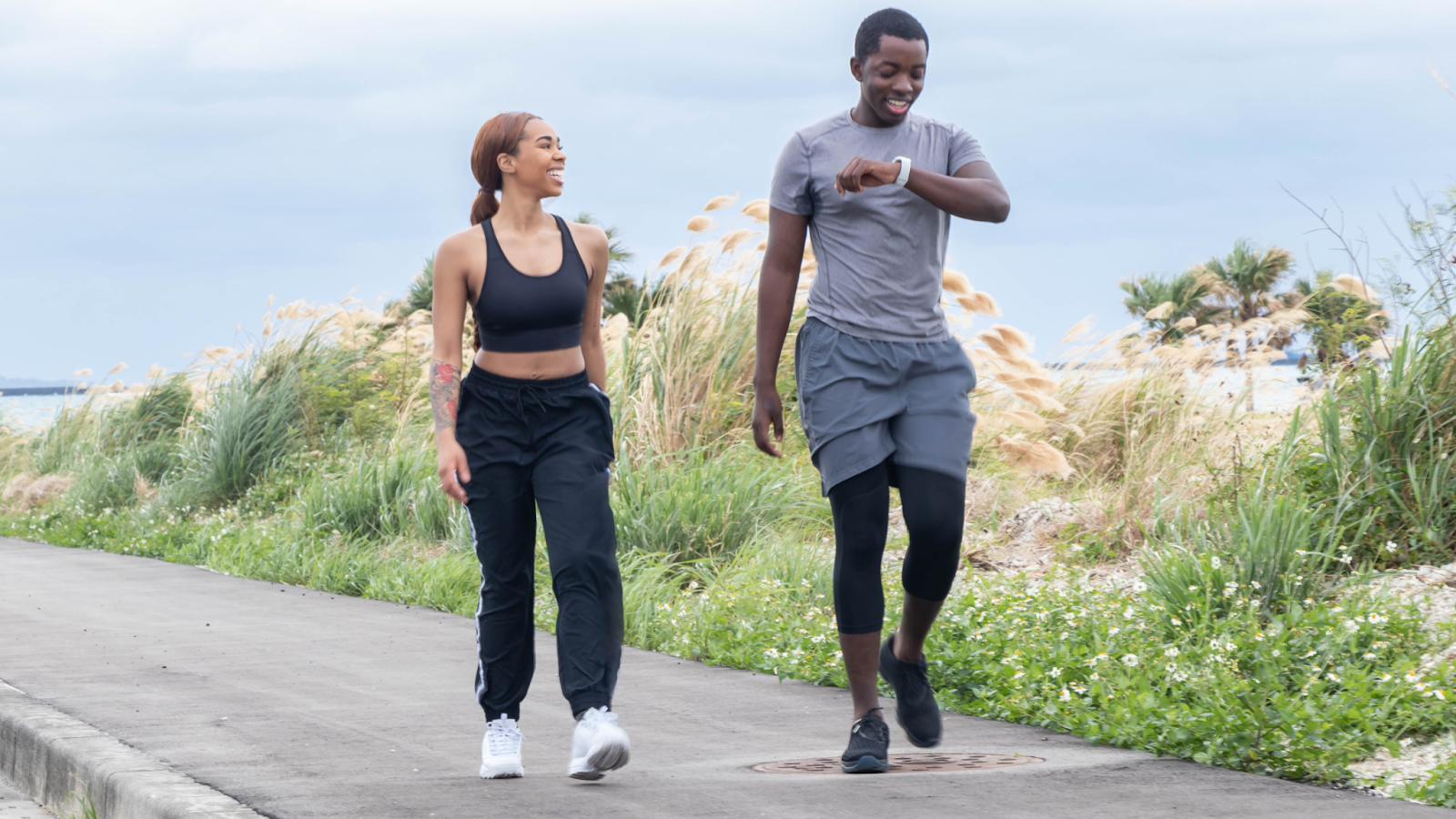 Man and woman out for a run and pacing themselves using a smart watch