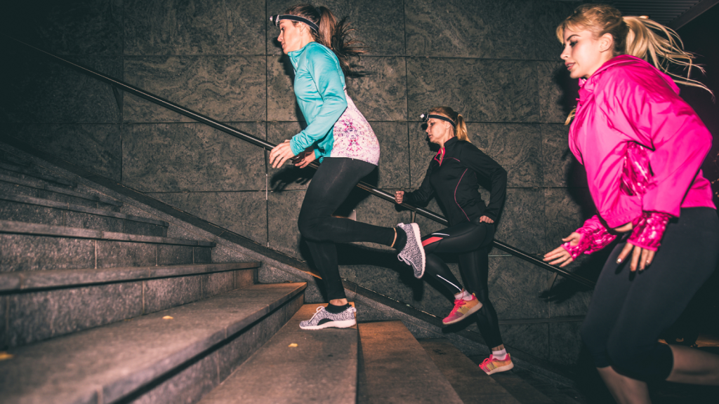 Three women running at night with reflective and bright clothes and LED lights