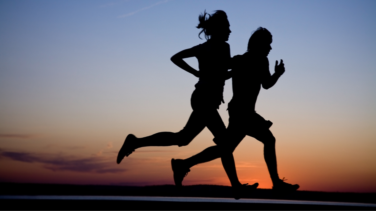 Man and woman running at sunset in the dark