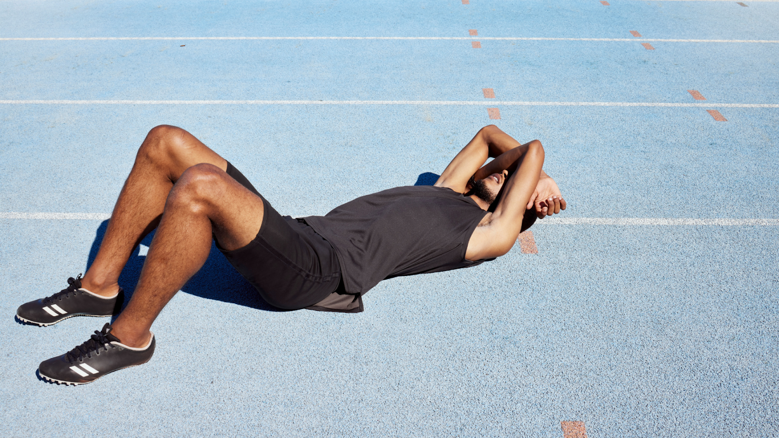 Man lying on the running track, exhausted and feeling burnt out