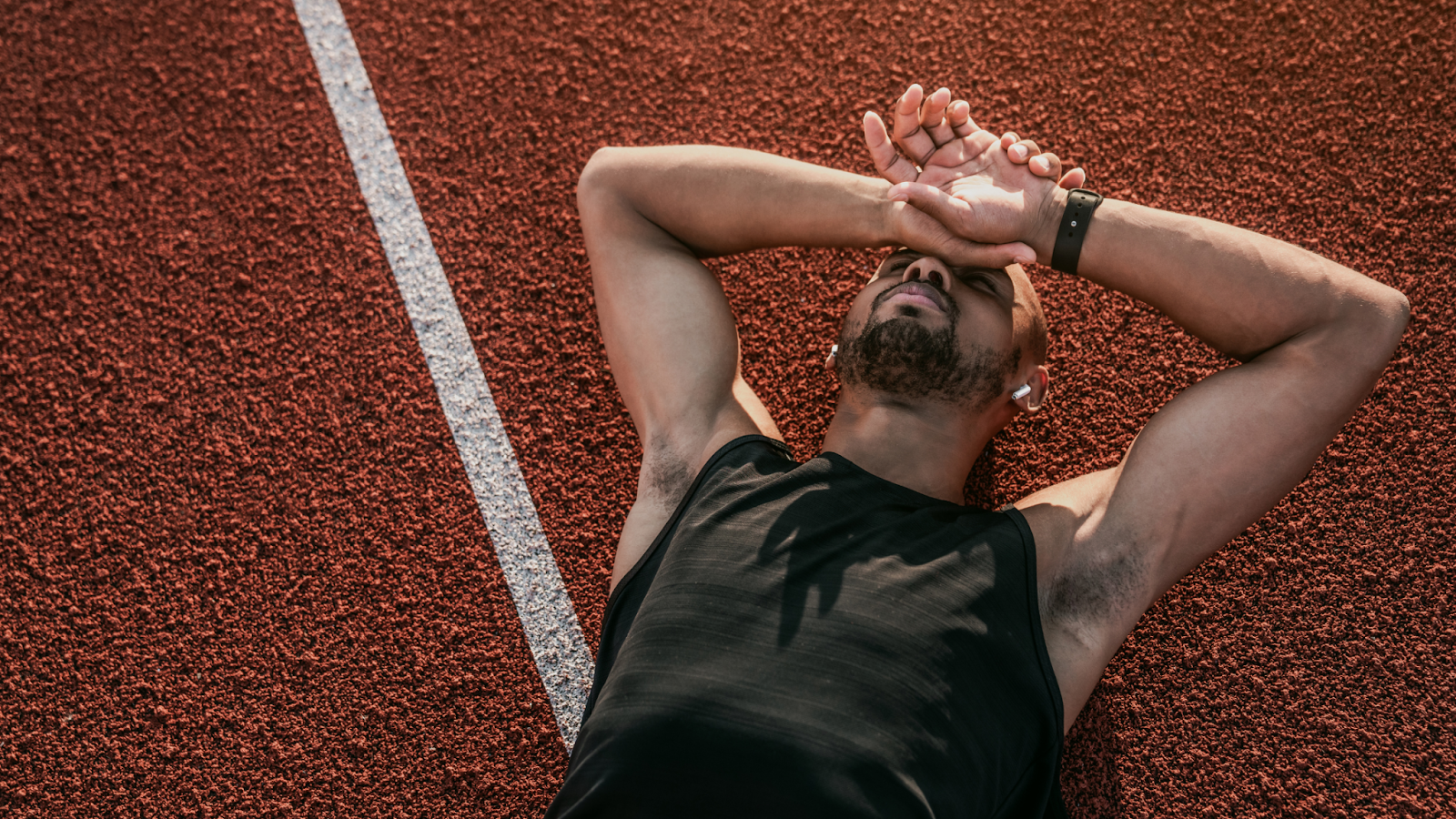 Man lying down on the running tracks, exhausted, doesn't want to run