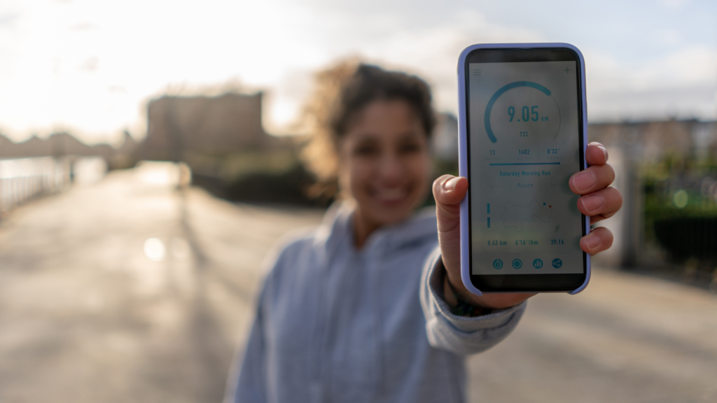 Woman holding up her phone to show her tracked running progress on an app