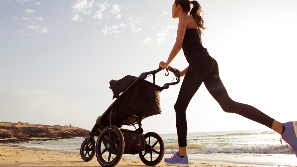 Woman running by the beach with her baby in a stroller