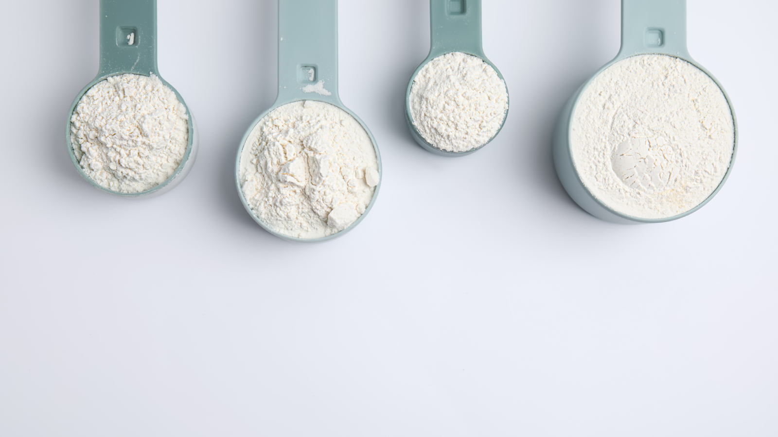 Different sized measuring spoons filled with creatine